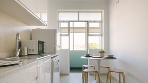 Uma cozinha moderna com armários brancos, micro-ondas, pia e janela com vista para o exterior.