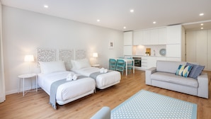 Una habitación de hotel moderna con dos camas, un sofá, un comedor y una kitchenette.