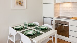 A modern kitchen with white cabinets, a built-in oven, and a dining area with a table set for four.