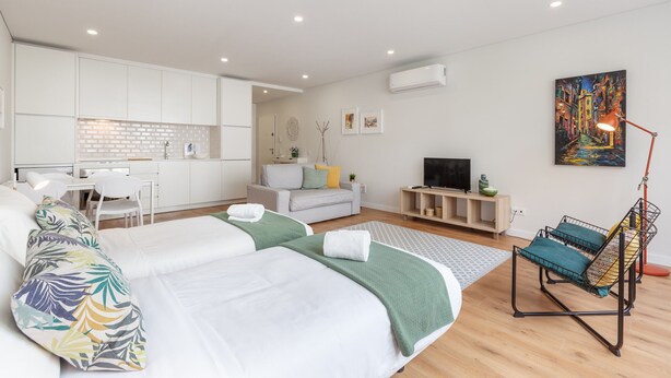 A modern hotel room with a large bed, a desk, a sofa, and a TV.
