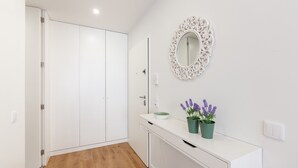 A modern bathroom with white cabinetry, a mirror with an ornate frame, and a potted lavender plant on the vanity.