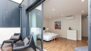 A modern bedroom with a glass door leading to a balcony, a bed with white bedding, a bedside table, and a wall-mounted air conditioner. - Oporto Palace Apartments Five (Oporto)