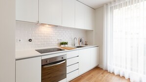 A modern kitchen with white cabinets, a wooden countertop, a built-in oven, and a sink. - Oporto Palace Apartments Five (Oporto)