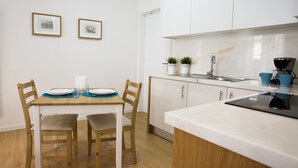 Una cocina moderna con armarios blancos, una mesa de comedor de madera con sillas y una cafetera.