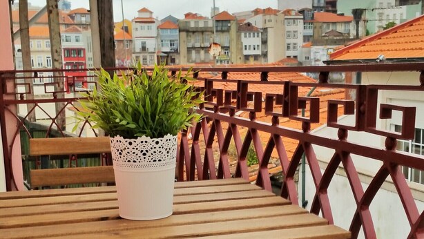 A wooden bench and table with a potted plant on a balcony with a red railing. - D&S - Crocodile House S. Bento Apartments IV (Oporto)