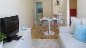 A modern living room with a flat-screen TV, a sofa, and a dining area with a table and chairs. - D&S - Crocodile House S. Bento Apartments IV (Oporto)