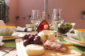 A table set with cheese, grapes, and a bottle of wine, with a green tablecloth and a pink wall in the background. - Alves da Veiga Apartments I (Oporto)