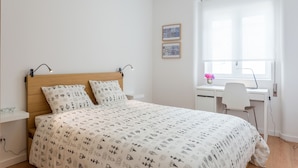 Een slaapkamer met een bed, een bureau en een stoel.