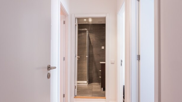 Een moderne hal met een douchecabine van glas die uitkomt op een badkamer.