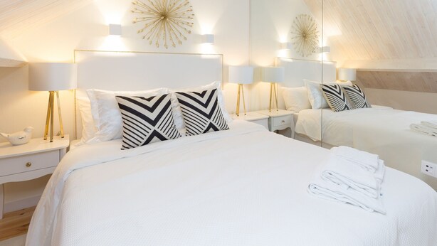 Una habitación de hotel con dos camas, ropa de cama blanca y lámparas de noche.