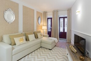A modern living room with a sectional sofa, a flat-screen TV, and a fireplace. - Loureiro Villas - A (Oporto)