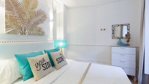 A bedroom with a bed, a nightstand, a mirror, and a wall art piece.
