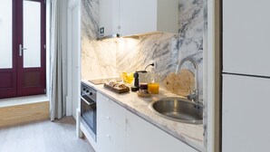 A modern kitchen with a marble backsplash, stainless steel sink, and a built-in oven.