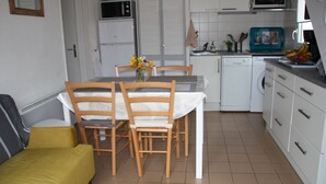 A compact kitchen with a dining table, chairs, a washing machine, and a microwave. - 1 Bedroom Villa in SAINT CYPRIEN PLAGE (SAINT CYPRIEN PLAGE)