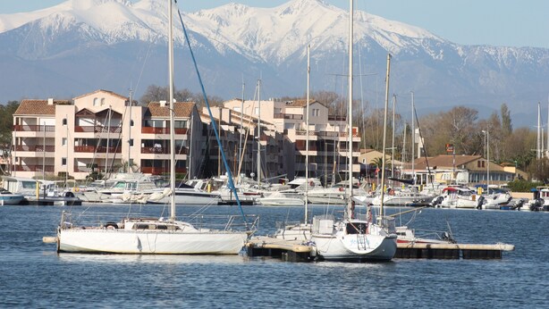 A marina with several boats docked, a mountainous backdrop, and buildings with balconies. - 1 Bedroom Villa in SAINT CYPRIEN PLAGE (SAINT CYPRIEN PLAGE)