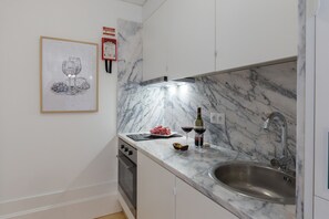 A kitchen with a marble countertop, stainless steel sink, and a framed artwork on the wall. - Loureiro Villas - D (Oporto)
