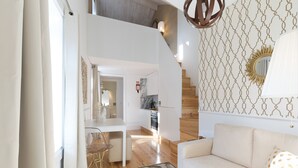 A modern living room with a white sofa, a patterned wall, and a wooden staircase.