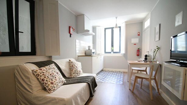 Un espace de vie compact comprenant un canapé, une petite table à manger et un téléviseur.