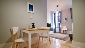 A dining area with a wooden table and chairs, a coffee machine, and a television in the background.