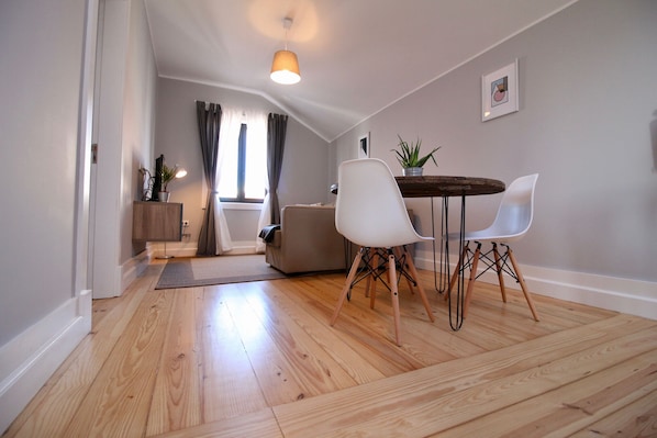A modern living room with a wooden floor, a dining table with chairs, a sofa, and a small side table with a plant. - Lapa 32 - Pedro IV (Oporto)