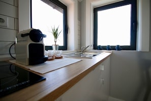 A kitchen with a countertop, a coffee maker, a plant, and a window with blinds. - Lapa 32 - Pedro IV (Oporto)