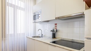 A modern kitchen with a built-in microwave, stainless steel sink, and black induction cooktop. - TRY OPORTO - Ponte do Infante (Oporto)