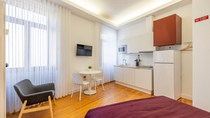 A compact hotel room with a bed, a small dining table, a chair, a kitchenette, and a TV. - TRY OPORTO - Ponte do Infante (Oporto)