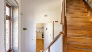A wooden staircase leading to a kitchen area with white cabinets and a visible window. - TRY OPORTO - Ponte Dom Luís (Oporto)