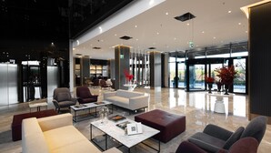Un vestíbulo amplio con mobiliario moderno, una recepción y ventanas grandes que ofrecen vistas al exterior.