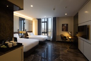 A hotel room with two beds, a desk, a chair, a TV, a coffee machine, and a window with a city view. - Bureau Collection Hotel  (Kartepe)