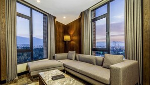 Una sala de estar moderna con un sofá modular, una mesa de centro de mármol y grandes ventanales con vistas a la ciudad.