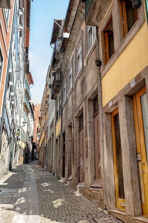 A narrow cobblestone street lined with historic buildings, featuring balconies and wooden doors. - Try Oporto Ribeira - Caves Port-Wine (Oporto)