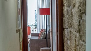 A narrow hallway leading to a living area with a sofa and a red lamp. - Try Oporto Ribeira - Barco Rabelo (Oporto)
