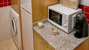 A compact kitchen with a microwave, coffee maker, and a washing machine. - Try Oporto Ribeira - Rio Douro (Oporto)