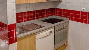 A kitchen with wooden cabinets, a stove, an oven, and a dishwasher. - Try Oporto Ribeira - Rio Douro (Oporto)