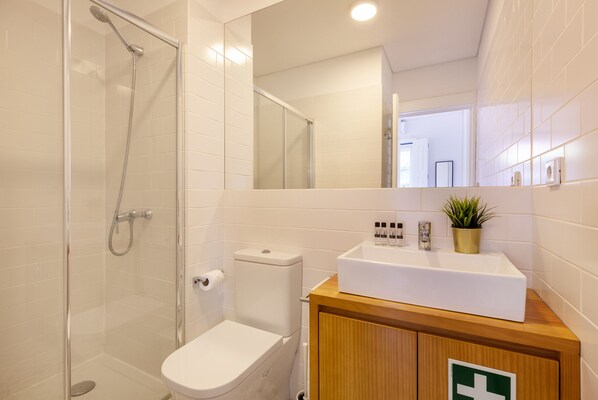 A modern bathroom with a glass-enclosed shower, a white toilet, and a wooden vanity with a sink.