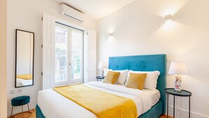 A bedroom with a bed, a nightstand, a lamp, a mirror, and a window. - D&S - Porto São Bento Apartments III (Oporto)