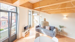 Una sala de estar moderna con un sofá gris, un televisor y un comedor con una mesa y sillas.