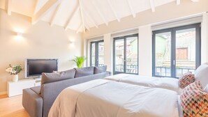 A modern hotel room with a large bed, a sofa, a TV, and a balcony with a view. - 12 Sweet Caroline 2 (Oporto)