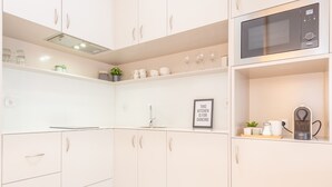 A modern kitchen with white cabinets, a microwave, and a coffee machine. - 12 Sweet Caroline 2 (Oporto)