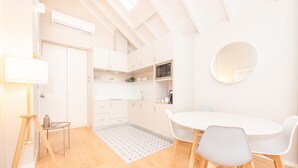 A modern kitchen with white cabinets, a round mirror, and a dining area with a white table and chairs. - 12 Sweet Caroline 2 (Oporto)
