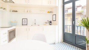 A modern kitchen with white cabinets, a built-in oven, and a window with a view of buildings.