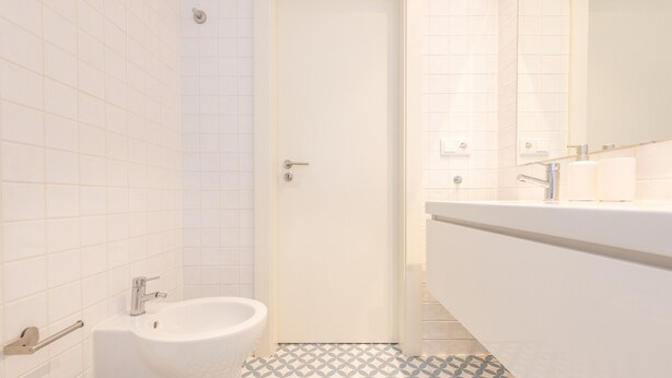A bathroom with a bidet, toilet, and a sink with a mirror.