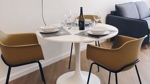 A dining area with a round table, two chairs, a wine bottle, and a modern pendant light. - Ático con Terraza 3.1 (Pontevedra)