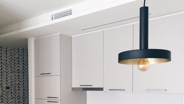 A modern kitchen with white cabinetry, a black pendant light, a built-in oven, and a stainless steel sink. - Ático con Terraza 3.1 (Pontevedra)