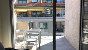 A balcony with a table and chairs, a view of neighboring buildings, and a clear sky. - Ático con Terraza 3.1 (Pontevedra)