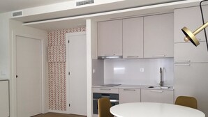 A modern kitchen with stainless steel appliances, a white dining table, and two chairs. - Loft con Terraza 3.2 (Pontevedra)