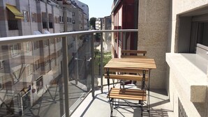 A balcony with a glass railing, a wooden table, and a chair. - Loft con Terraza 3.2 (Pontevedra)