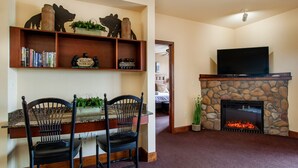 A living room with a stone fireplace, a television, and a bookshelf with books and decorative items. - The Bear Paw Palace - Mtn View & Community Pools! (Pigeon Forge)