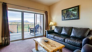 A living room with a leather sofa, a wooden coffee table, and a painting on the wall. - The Bear Paw Palace - Mtn View & Community Pools! (Pigeon Forge)